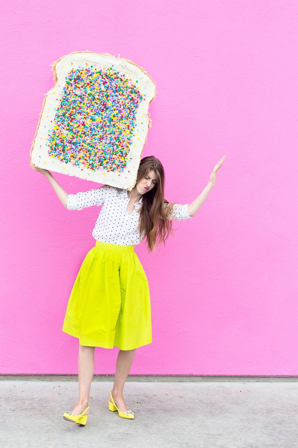 A woman in a yellow skirt and holding a fairy bread pinata 