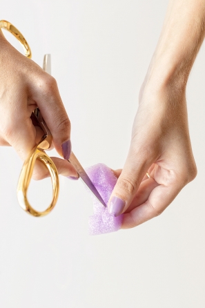 Someone cutting a purple styrofoam ring 