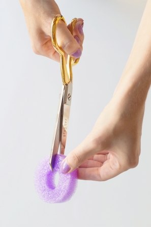 Someone cutting a purple styrofoam ring 