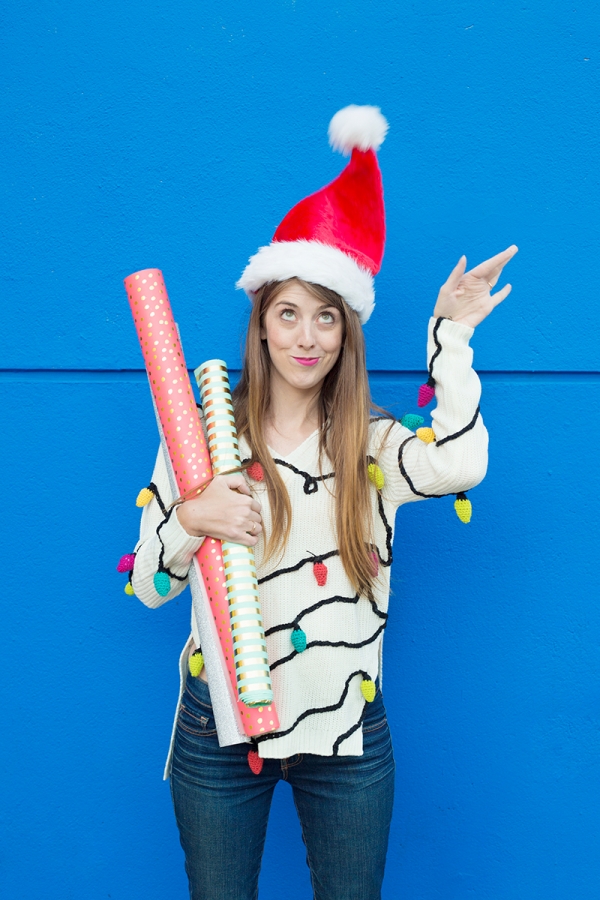 A woman wearing a santa hat and holding wrapping paper