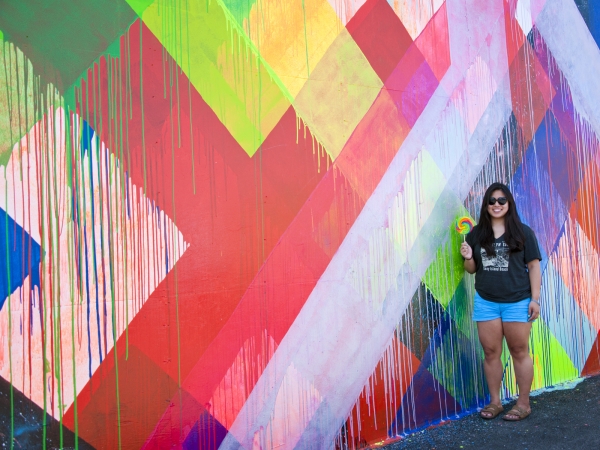 A woman standing in front of a colorful mural 