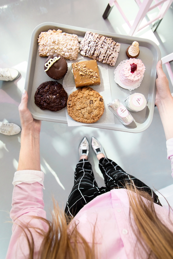 A woman holding a tray of desserts