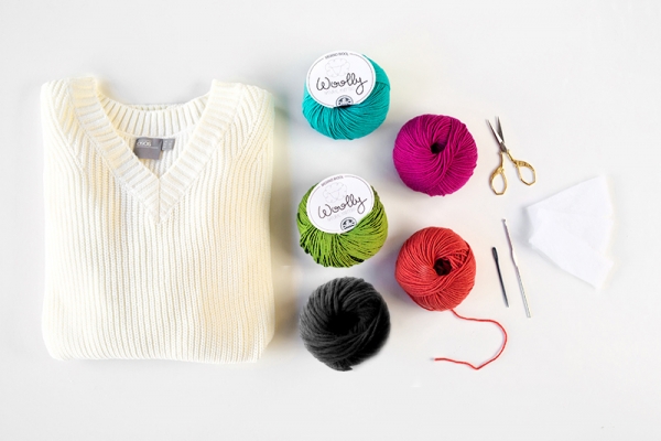 A white sweater, yarn, and scissors 