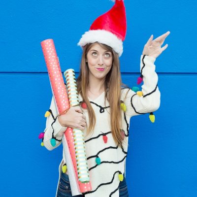 A woman wearing a santa hat and holding wrapping paper