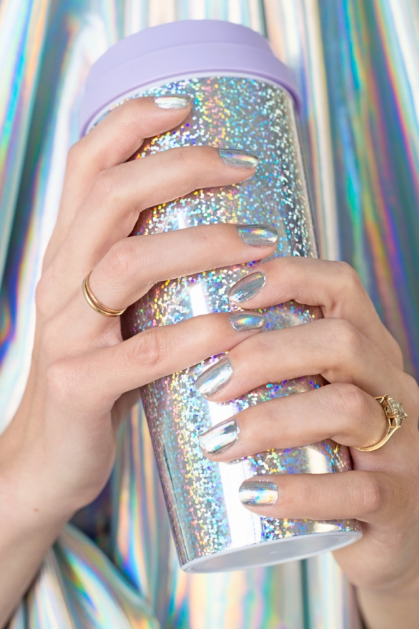 A woman holding a silver cup with silver nails