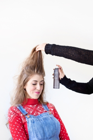 Someone using hairspray in a woman\'s hair