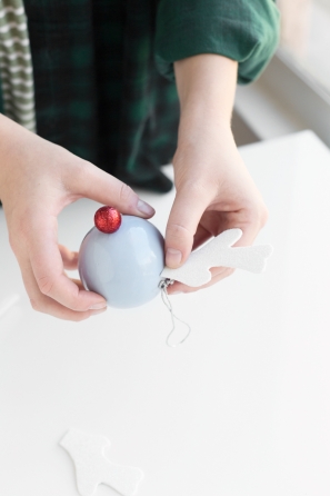 Someone gluing a white object on a purple ornament 