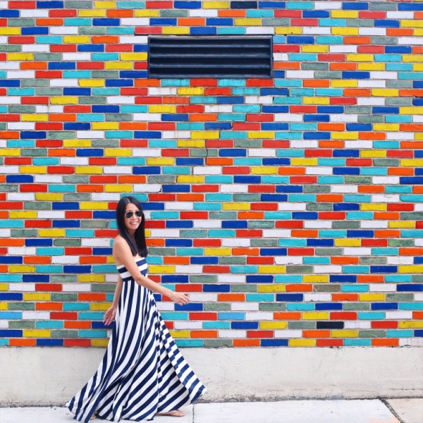 A woman standing in front a wall with colorful tiles