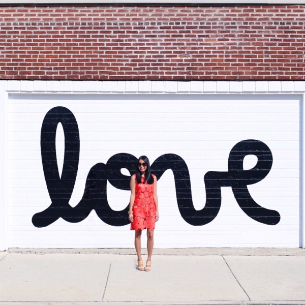 A woman standing in front of a wall that says \"love\"