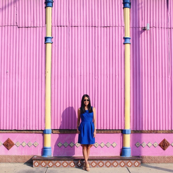 A woman standing in front of a pink wall