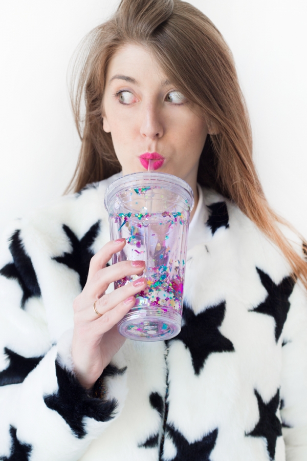 A woman holding a cup with glitter on it