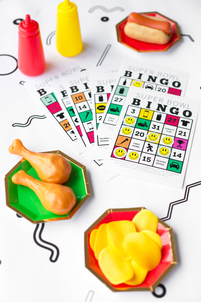 super bowl bingo cards with fake food on plates on white patterned table