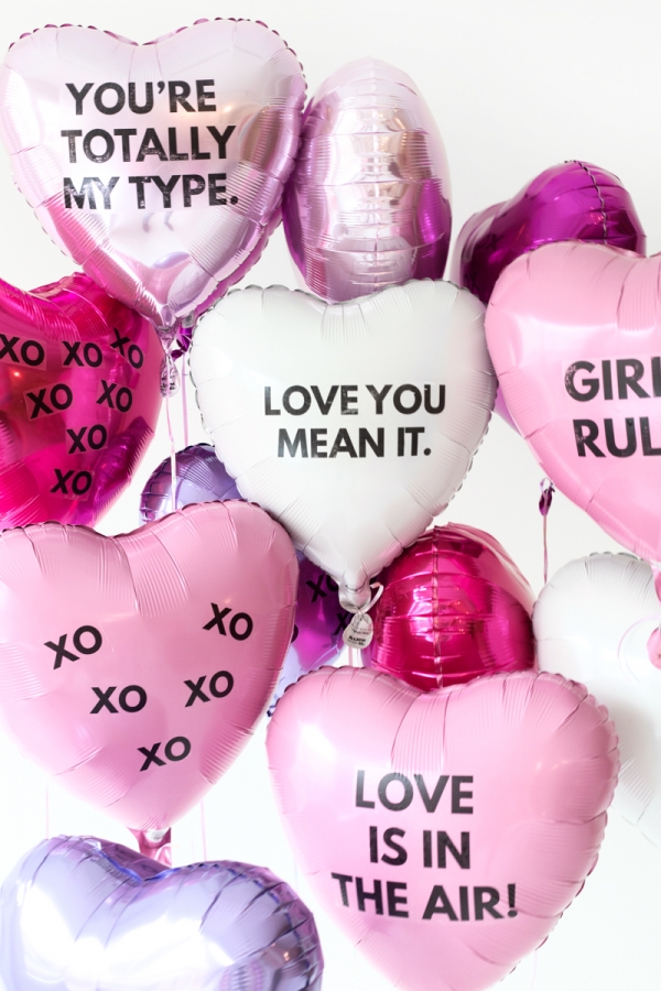 A bunch of pink and white balloons with words on them