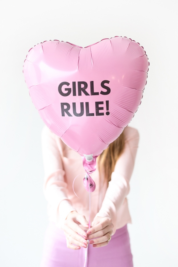 Someone holding a pink balloon that says girls rule