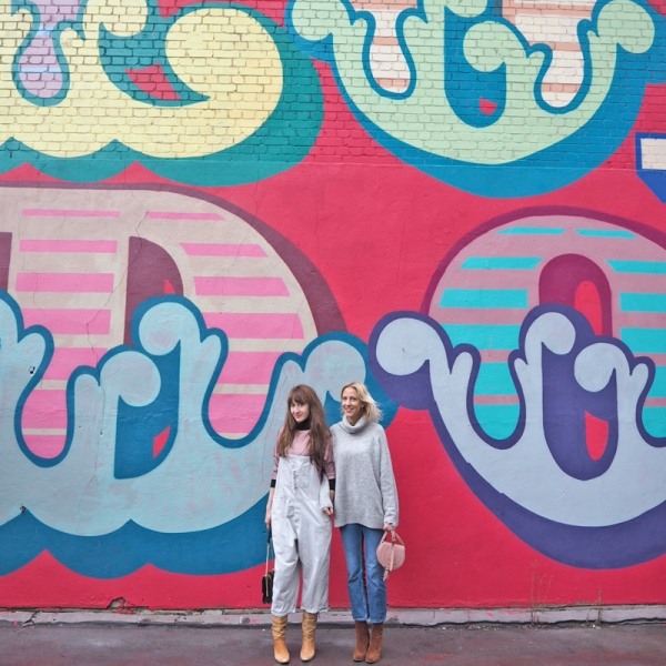 Two people standing in front of a colorful mural