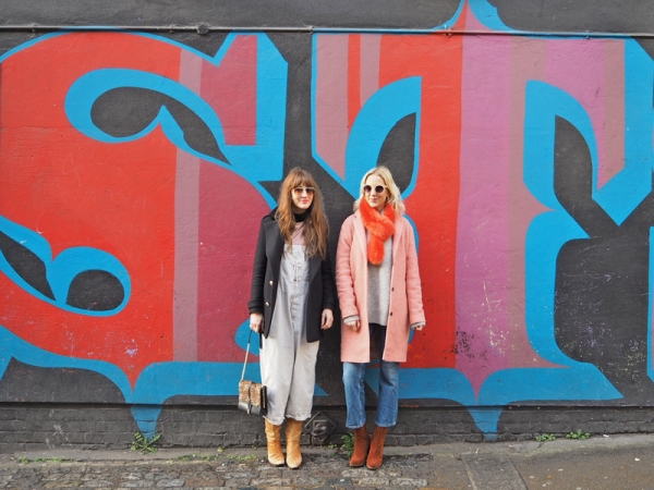 Two girls standing in front of a colorful wall