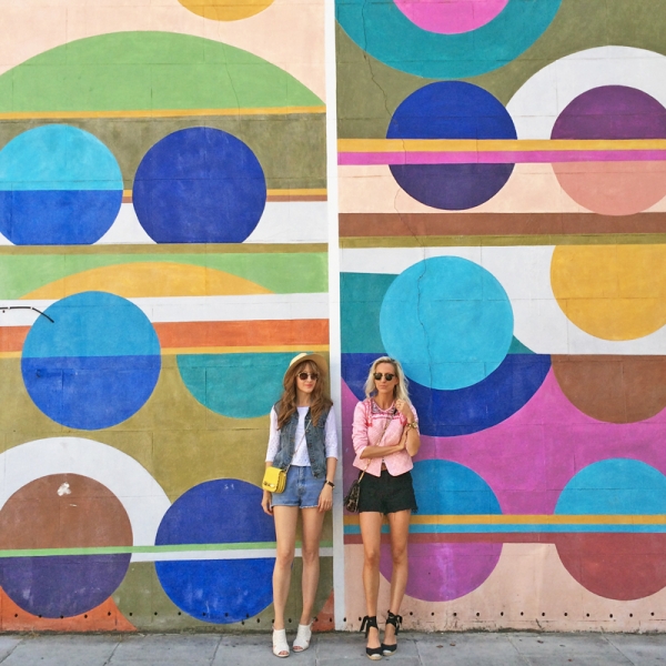 Two people standing in front of a colorful mural