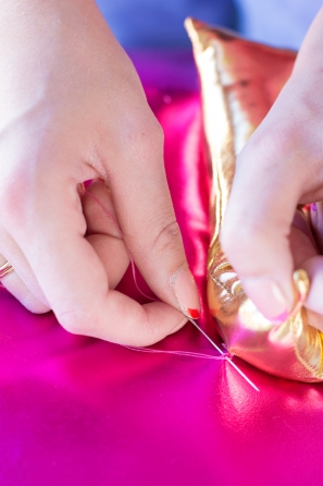 Someone sewing gold fabric