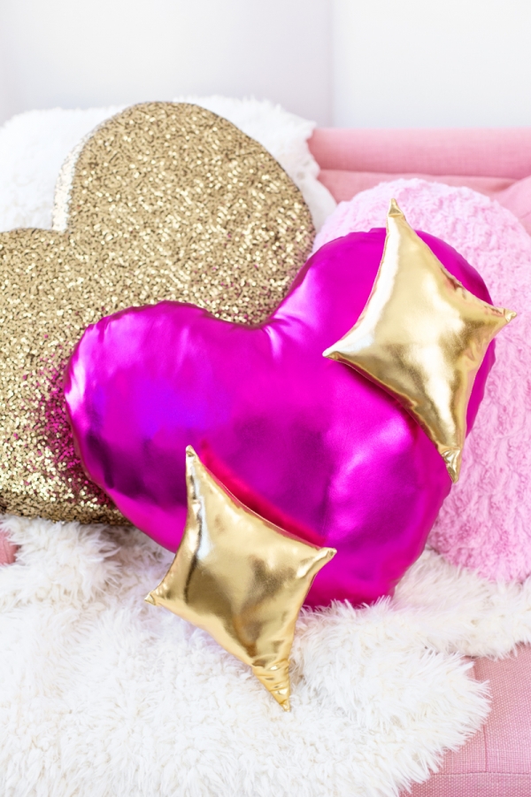 A shiny pink heart-shaped pillow with stars