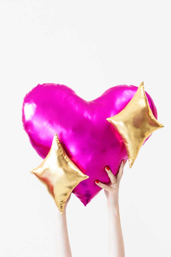 Someone holding a pink heart pillow with gold stars