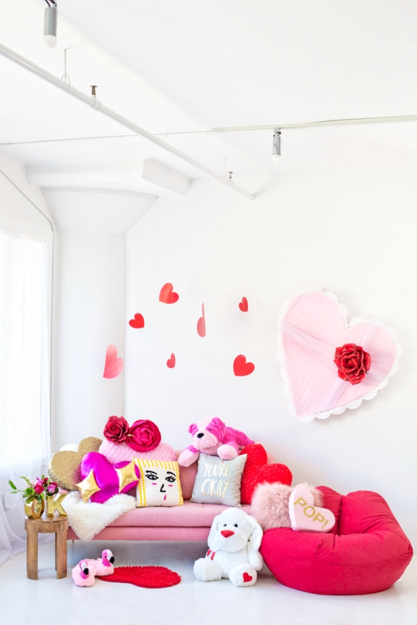 A bunch of hearts hanging from the ceiling and a couch with pillows