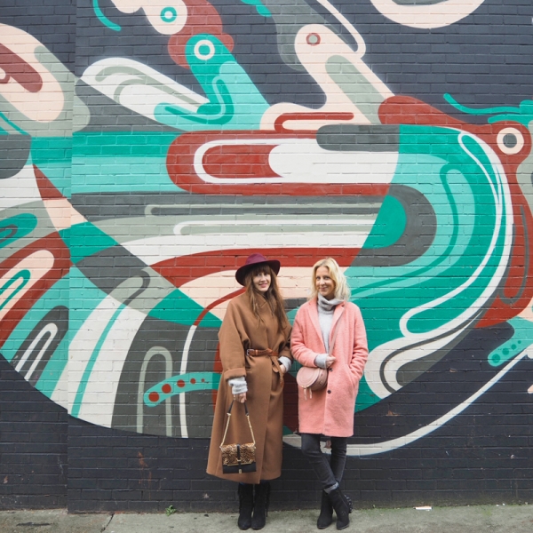 Two people standing in front of a colorful mural
