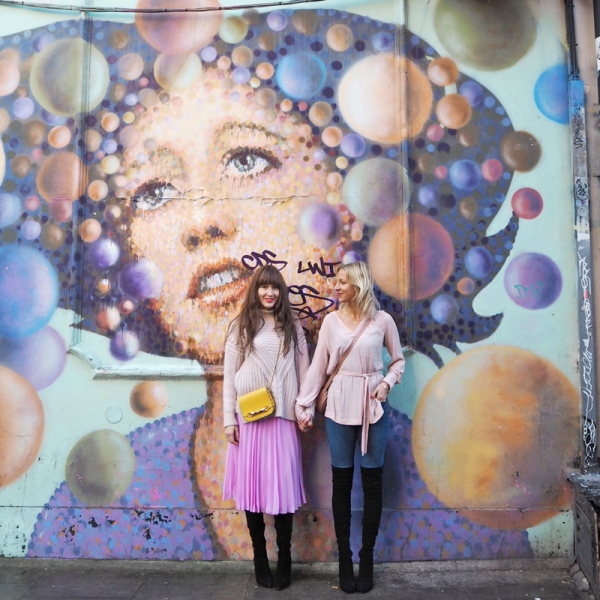 Two people standing in front of a colorful mural