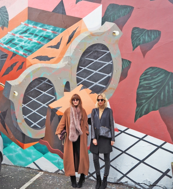 Two girls standing in front of a mural