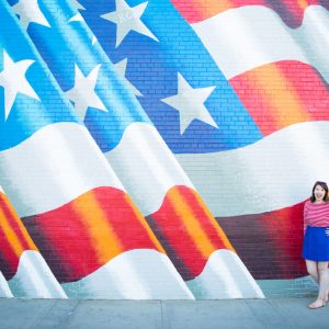 A woman standing in front of an American flag mural