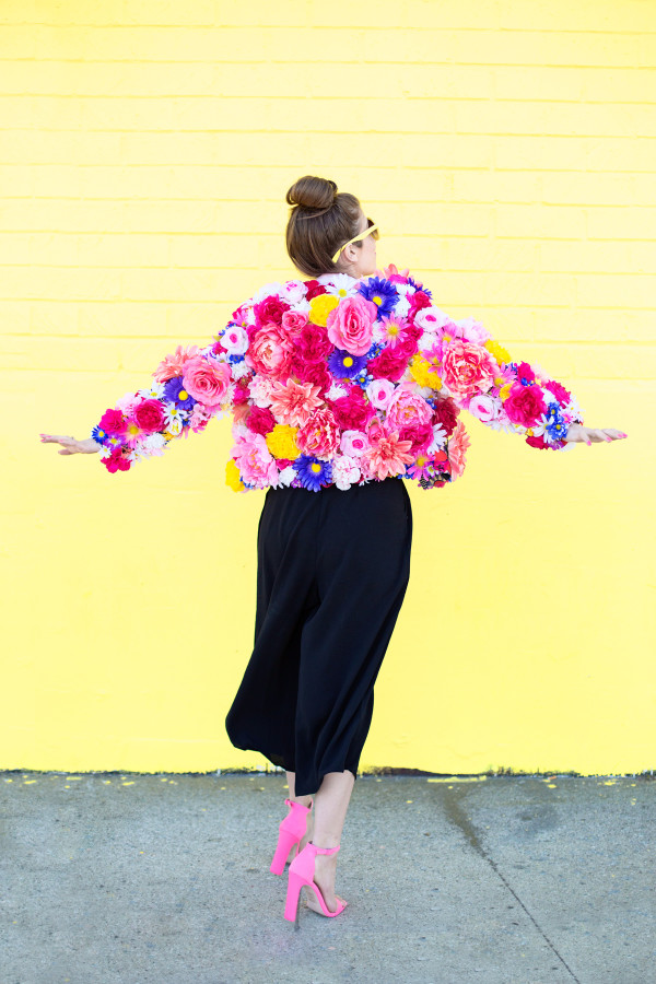 A woman wearing a floral jacket in front of a yellow wall
