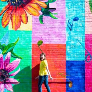 A woman in front of a colorful wall