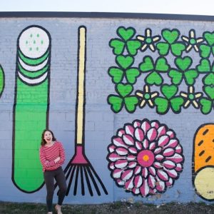 A woman in front of a colorful mural
