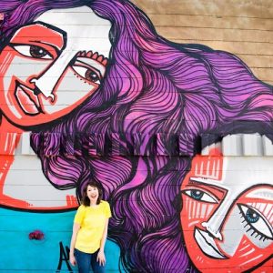 A woman standing in front of a mural