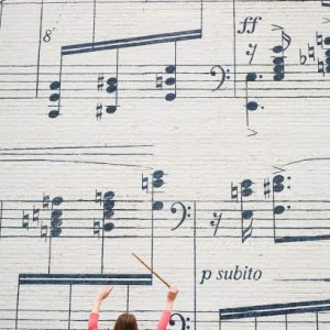 A woman standing in front of a music sheet mural