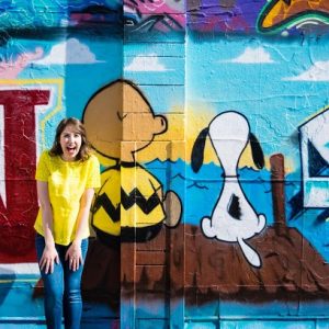 A woman standing in front of charlie brown mural