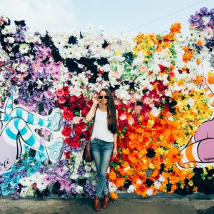 A woman standing in front of a floral mural