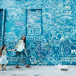 A woman and her daughter standing in front of a blue mural