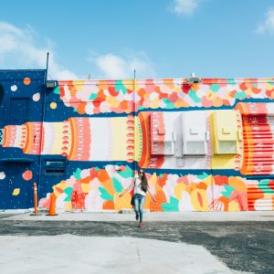 A woman standing in front of a colorful mural