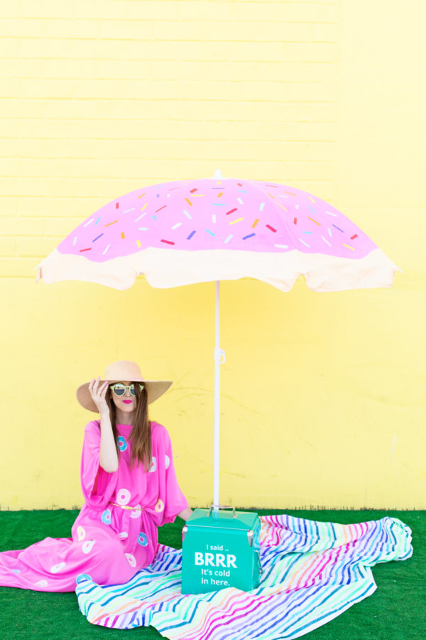 A woman sitting under a pink umbrella