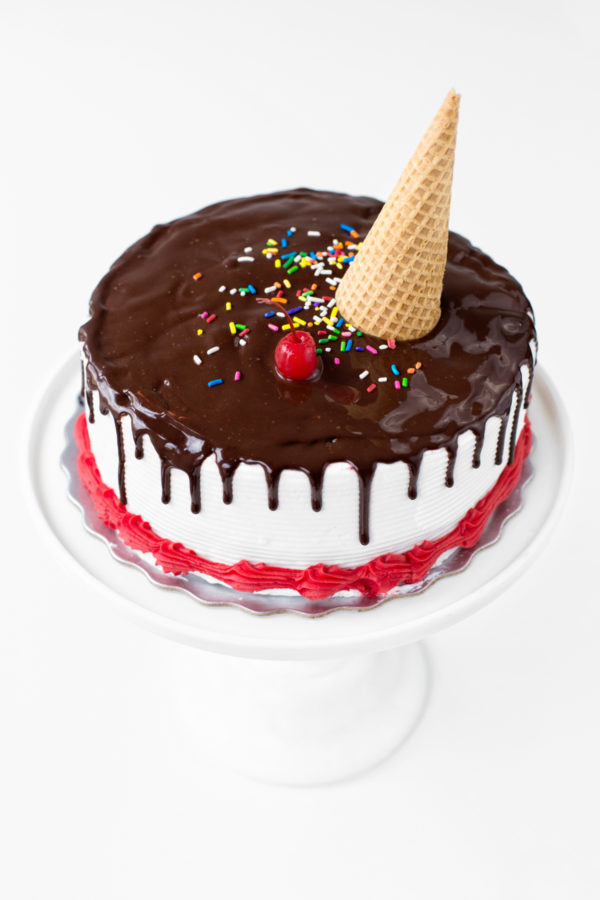 A cake with red frosting and chocolate syrup 