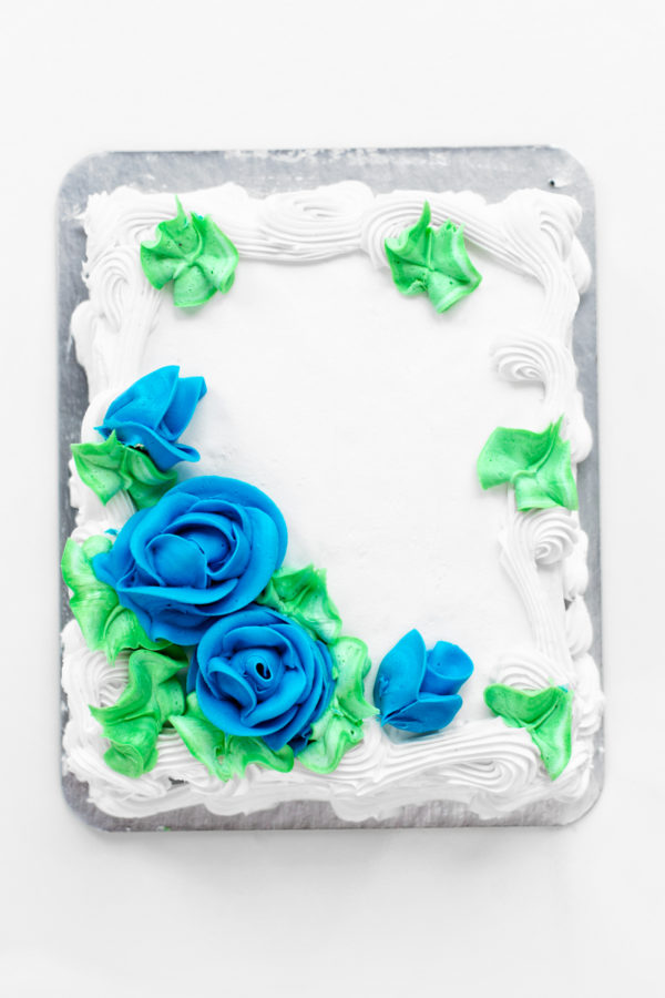A white cake with blue flower frosting