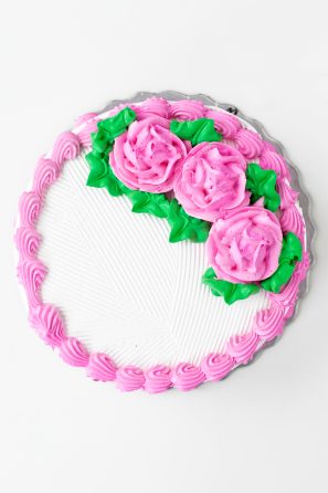 A cake with white frosting and pink frosted flowers 