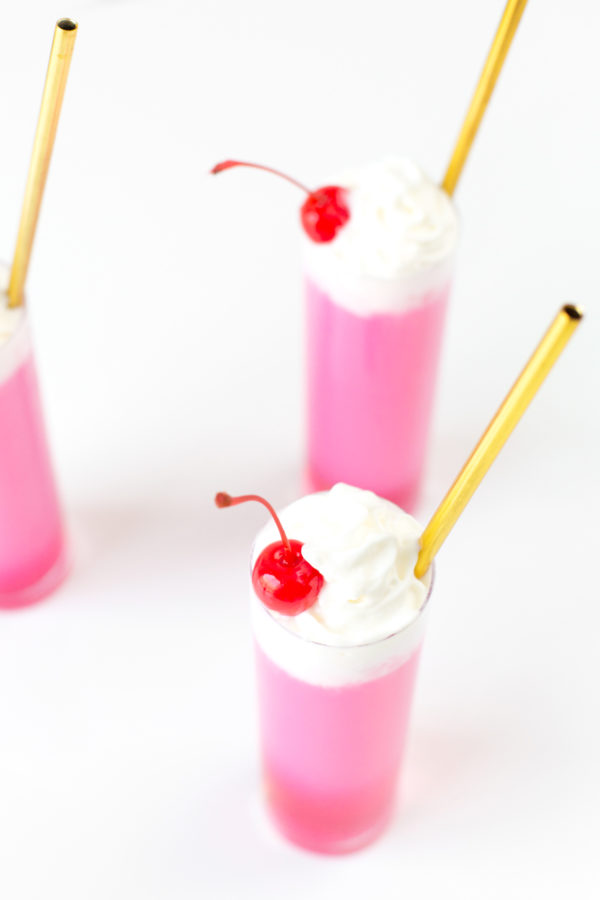 Three glasses with gold straws and pink liquid 