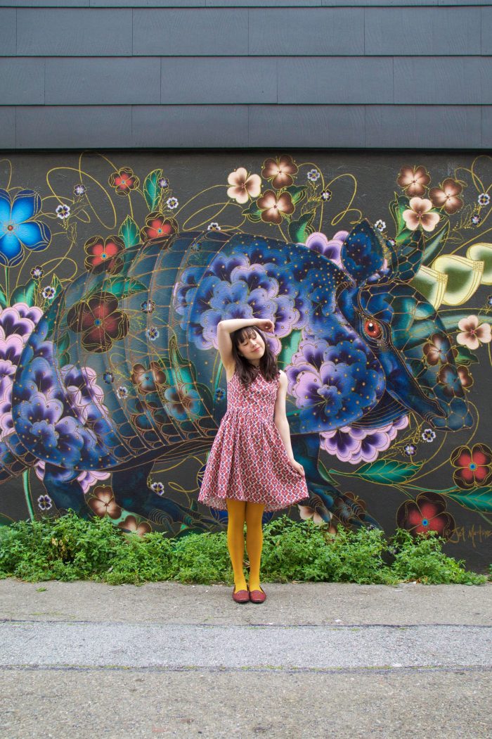 A woman standing in front of a floral mural
