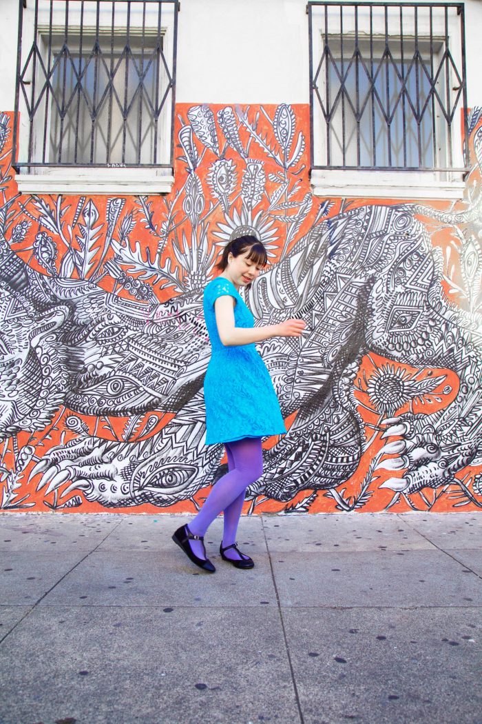 A woman standing in front of a colorful mural