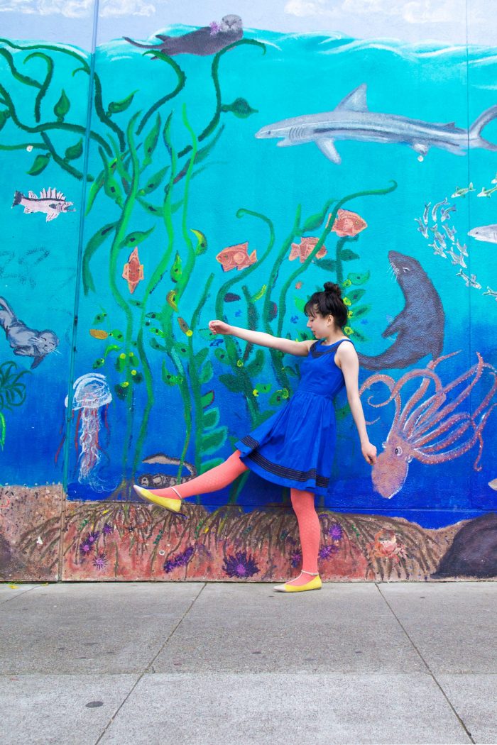 A woman standing in front of a under the sea mural