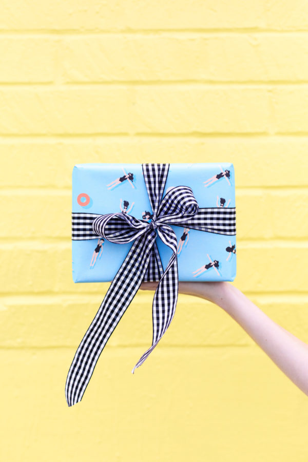 Someone holding a present in front of a yellow wall