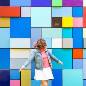 A woman in front of a very colorful wall