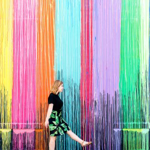 A woman in front of a rainbow wall
