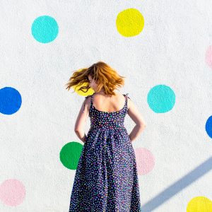A woman in a dress in front of a wall with polka dots